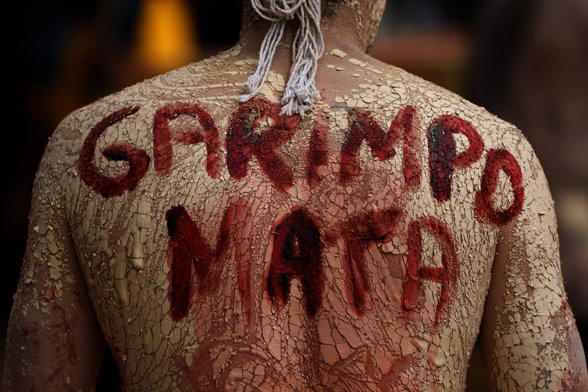 FILE - An Indigenous man with the phrase painted on its back that reads in Portuguese "Mining Kills," participates in a protest against the increase of mining activities that are encroaching ...
