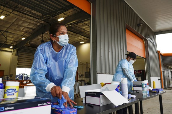 Testing worker Yolanda Aleman grabs a pair of gloves as she prepares to perform COVID-19 antigen tests Thursday, Dec. 30, 2021, at a testing site for Cameron County in La Feria, Texas. (Denise Cathey/ ...