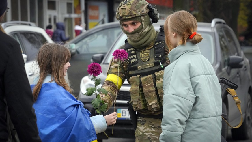 A girl wrapped in the national flag exchange flowers with a Ukrainian soldier in central Kherson, Ukraine, Sunday, Nov. 13, 2022. The Russian retreat from Kherson marked a triumphant milestone in Ukra ...
