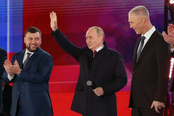 Russian President Vladimir Putin, center, waves as Denis Pushilin, leader of self-proclaimed of the Donetsk People's Republic, left, and Moscow-appointed head of Kherson Region Vladimir Saldo, right, stand near him during celebrations marking the incorporation of regions of Ukraine to join Russia in Red Square, in Moscow, Russia, Friday, Sept. 30, 2022. The signing of the treaties making the four regions part of Russia follows the completion of the Kremlin-orchestrated &quot;referendums.&quot; (Sergei Karpukhin, Sputnik, Kremlin Pool Photo via AP)