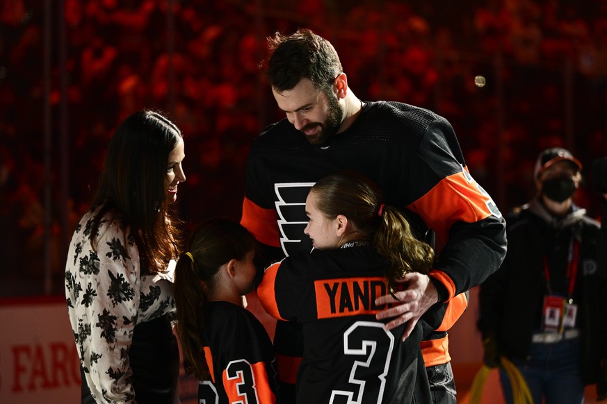 Philadelphia Flyers' Keith Yandle, right, receives a hug from his family as he is honored on ice prior to an NHL hockey game against the Los Angeles Kings, Saturday, Jan. 29, 2022, in Philadelphi ...
