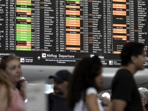 epa11487356 Passengers look at screens informing on the flight situation at the Zurich Airport in Kloten, Switzerland, 19 July 2024. Due to a major worldwide IT outage, check-in for air travelers and  ...