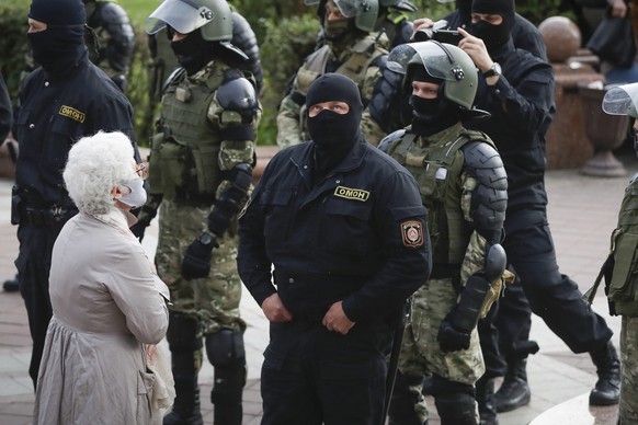 A woman reacts in front of a riot police blockade during a protest at the Independence Square in Minsk, Belarus, Thursday, Aug. 27, 2020. Police in Belarus have dispersed protesters who gathered on th ...