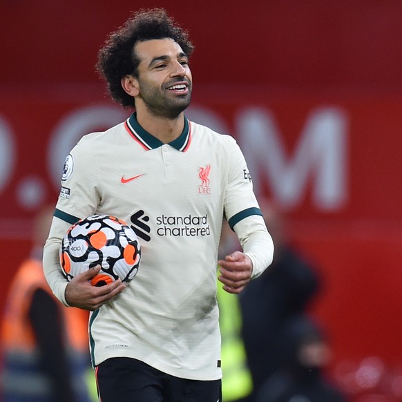 epa09544076 Liverpool's Mohamed Salah (L) carries the matchball as he celebrates after the English Premier League soccer match between Manchester United and Liverpool FC in Manchester, Britain, 24 Oct ...
