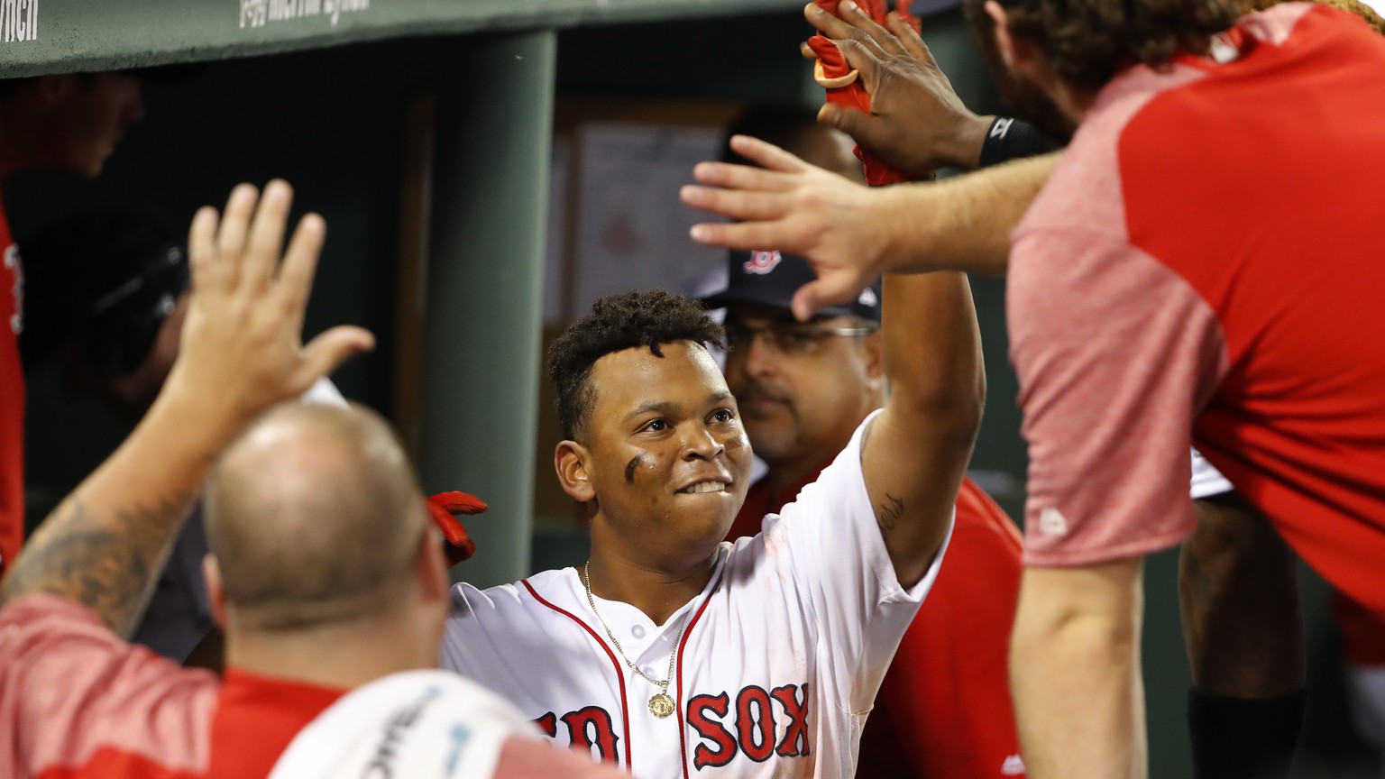 Boston Red Sox&#039;s Rafael Devers is congratulated in the dugout after his home run against the New York Yankees during the seventh inning of a baseball game at Fenway Park in Boston on Saturday, Au ...