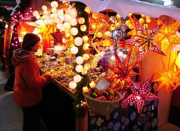 Eine Frau bestaunt am Samstag, 24. Dezember 2005, auf dem Weihnachtsmarkt im Zuercher Hauptbahnhof den Lichterglanz zahlreicher Sterne. (KEYSTONE/Steffen Schmidt)