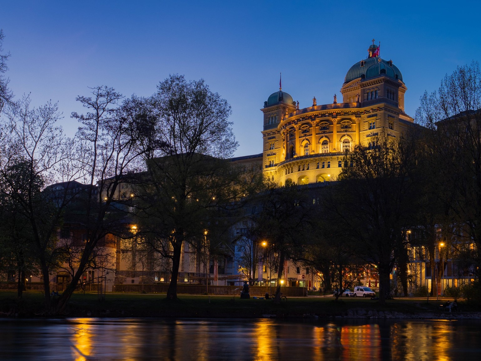 Berne, Switzerland - April 15th 2023: Evening view over the Aare river towards Bundeshaus, lighted during blue hour The city of Berne, Switzerland, is the location of the Swiss government. View over t ...