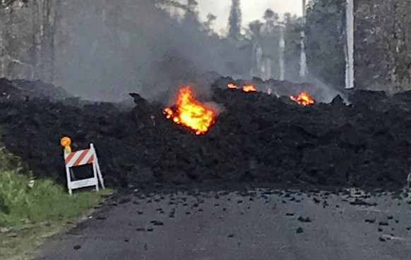 This photo provided by Hawaii Electric Light shows lava flowing over Mohala Street in the Leilani Estates area near Pahoa on the Big Island of Hawaii Friday, May 4, 2018. Nearly 1,500 people have fled ...