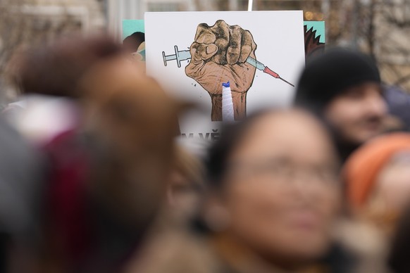 People hold up a banner as they gather to protest against the governments restrictions to curb the spread of COVID-19 in Prague, Czech Republic, Sunday, Jan. 9, 2022. (AP Photo/Petr David Josek)