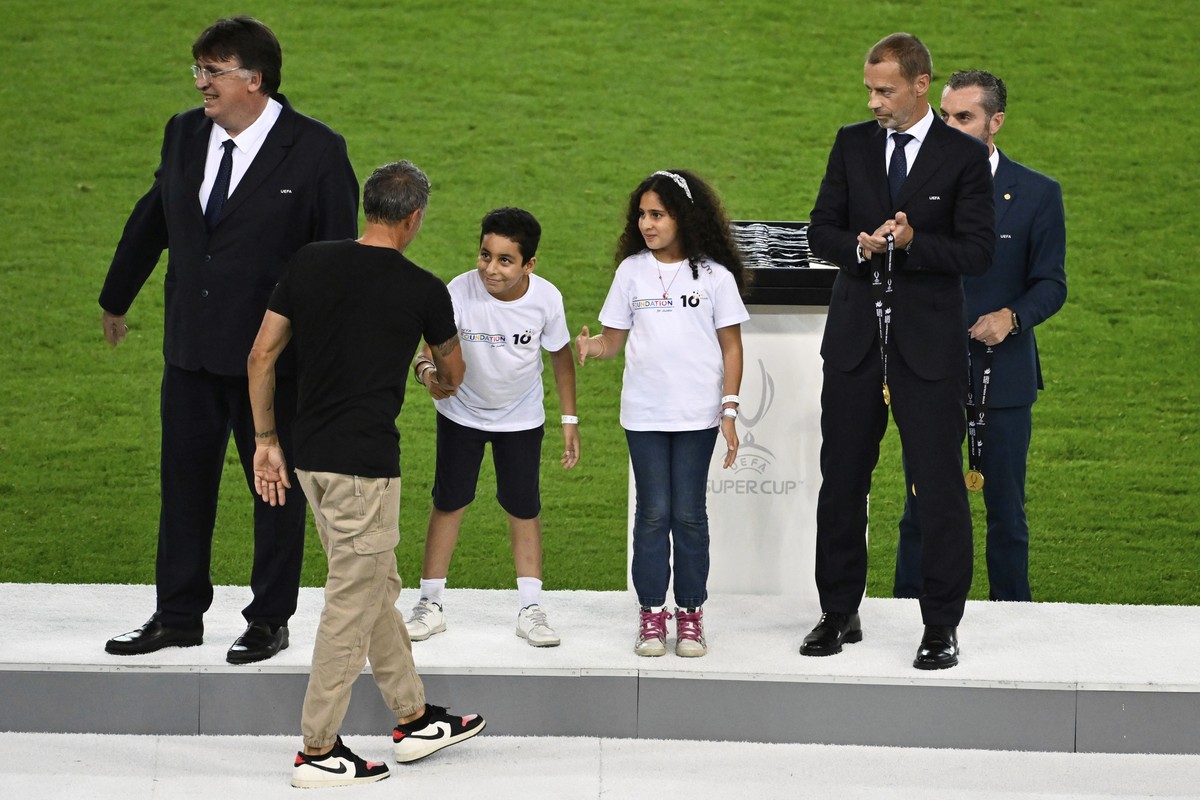 PSG's coach Luis Enrique shakes hands with Palestinian refugee children Tala, 12 years-old and Mohamed, 9 years-old, standing next to UEFA President Aleksander Ceferin, right, during the medals a ...
