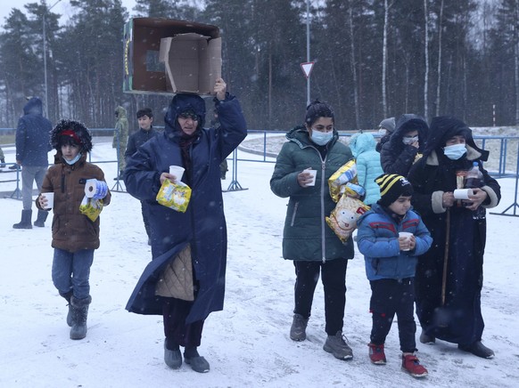 Migrants carry a food at a logistics center at the checkpoint logistics center &quot;Bruzgi&quot; at the Belarus-Poland border near Grodno, Tuesday, Nov. 30, 2021. The West has accused Belarusian Pres ...