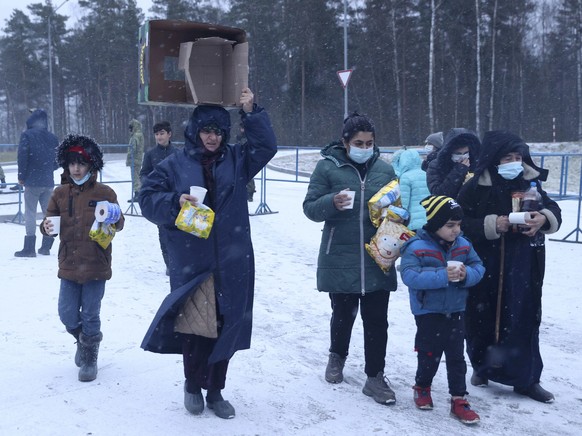Migrants transport food to a logistics center at the checkpoint logistics center "bruzgi" at the border between Belarus and Poland near Grodno, Tuesday, November 30, 2021. The West has accused the Belarusian president ...
