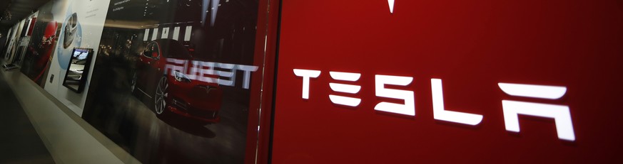 FILE - This Feb. 9, 2019, file photo shows a sign bearing the company logo outside a Tesla store in Cherry Creek Mall in Denver. U.S. auto safety regulators are looking into a complaint from a Tesla d ...