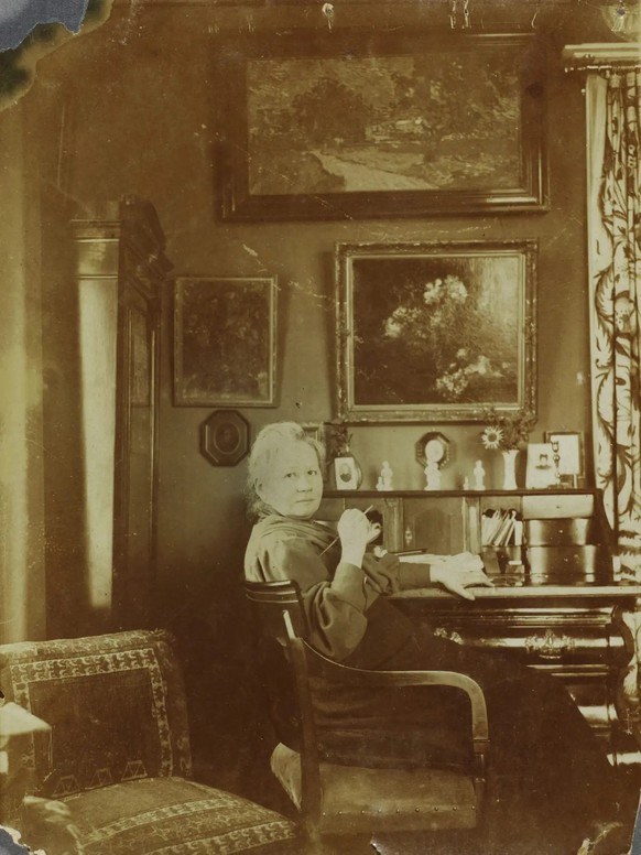 Jo van Gogh-Bonger im Wohnzimmer ihres Hauses am Koniginnenweg 77 in Amsterdam (1990 oder später). An der Wand über dem Sekretär zwei Bilder von Schwager Vincent, «Vase mit Mondviolen» (1884) und «Lan ...