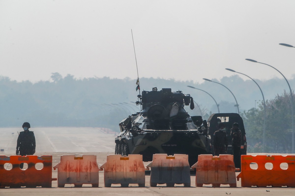 Myanmar's soldiers stand guard at a roadblock manned with an armored vehicle in a road leading to the parliament building Tuesday, Feb. 2, 2021, in Naypyitaw, Myanmar. Hundreds of members of Myan ...