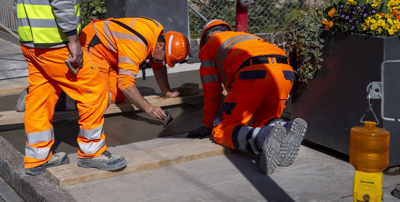 Construction workers work without keep social distance as recommended by Swiss authority as a precaution against the spread of the coronavirus COVID-19, in Carouge near Geneva, Switzerland, Wednesday, ...