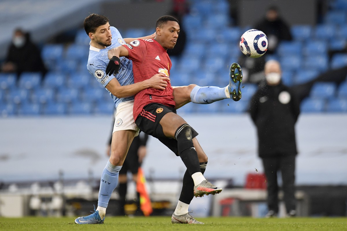 Manchester City's Ruben Dias, left, fights for the ball with Manchester United's Anthony Martial during the English Premier League soccer match between Manchester City and Manchester United  ...