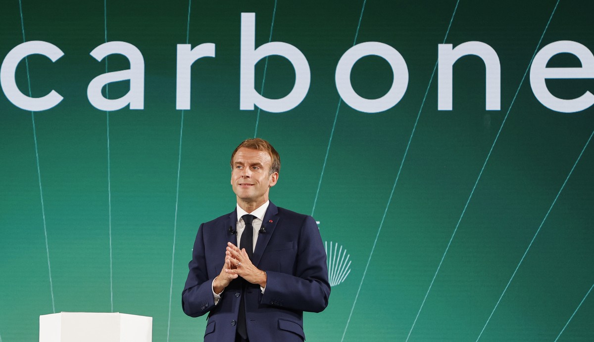 epa09519731 France's President Emmanuel Macron speaks in front of a screen with the word "Carbon" during the presentation of "France 2030" investment plan at The Elysee Presid ...