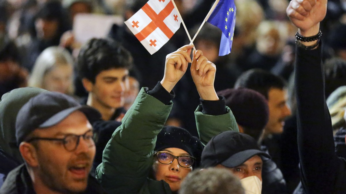 A young woman holds a Georgian national flag and an EU flag during a rally against a draft law aimed at curbing the influence of "foreign agents" near the Georgian parliament building in Tbi ...