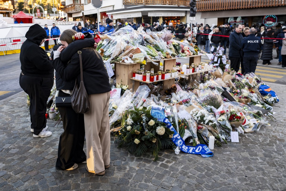 epa12623757 Mourners observe floral tributes to the victims on the site of the fire at the 'Le Constellation' bar and lounge, in Crans-Montana, Switzerland, on Saturday, January 3, 2026. 40  ...