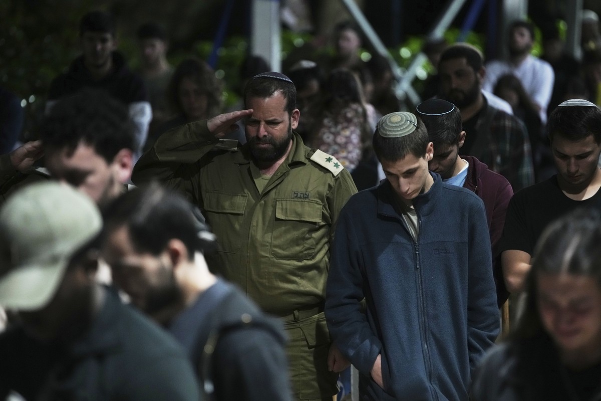 People stands still to observe a minute of silence as a siren sound marks the beginning of Israel's annual Memorial Day for the fallen soldiers at Mount Herzl military cemetery in Jerusalem, Tues ...
