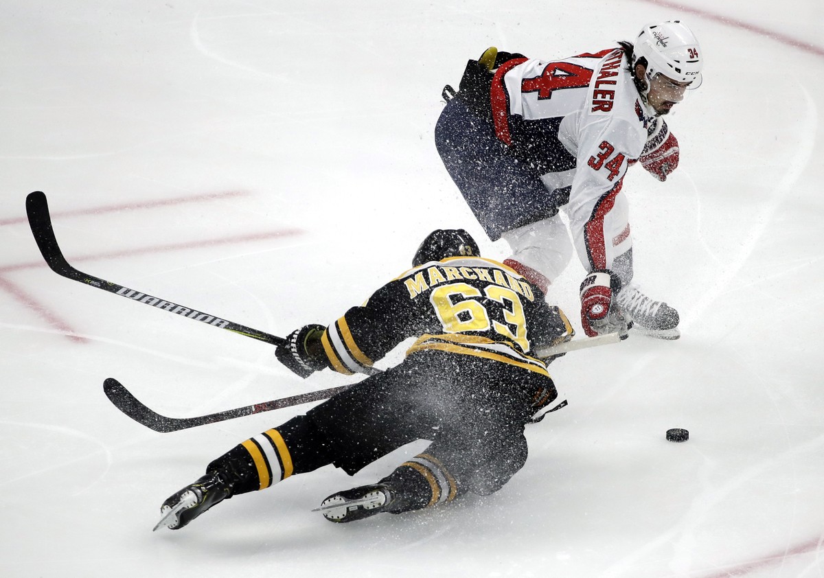 Boston Bruins left wing Brad Marchand (63) is dumped to the ice by Washington Capitals defenseman Jonas Siegenthaler (34) near the Capitals' goal during the first period of an NHL hockey game Thu ...