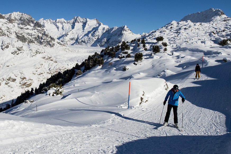 epa04544389 Skiers are descending on a slope with the Aletsch glacier on the background during a sunny day in the Swiss Alps in the Aletsch area in Riederalp, Switzerland, 01 January 2015. EPA/JEAN-CH ...