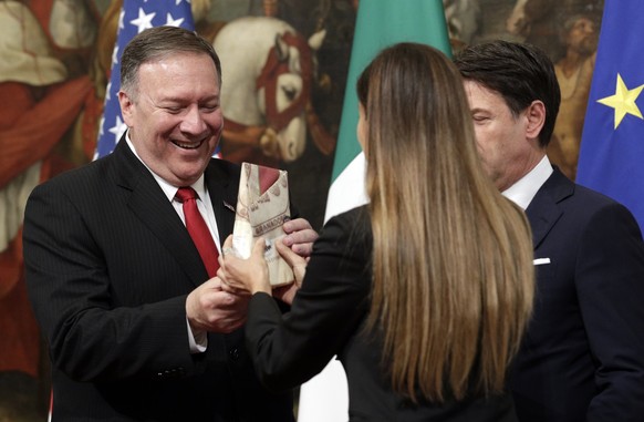 U.S. Secretary of State Mike Pompeo is given a package of Parmesan cheese as Italian Premier Giuseppe Conte, right, looks on, following their meeting at Chigi Palace premier&#039;s office in Rome, Tue ...
