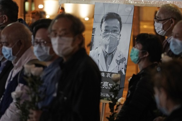 People wearing masks, attend a vigil for Chinese doctor Li Wenliang, in Hong Kong, Friday, Feb. 7, 2020. The death of a young doctor who was reprimanded for warning about China's new virus trigge ...