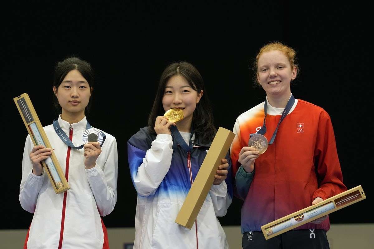 Gold medalist South Korea's Ban Hyojin, center, silver medalist China's Huang Yuting, left, and Switzerland's Audrey Gogniat celebrate after recieving their medals after the 10m air rif ...