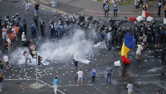 Riot police fires teargas into the crowds during protests outside the government headquarters, in Bucharest, Romania, Friday, Aug. 10, 2018. Romanians who live abroad are staging an anti-government pr ...