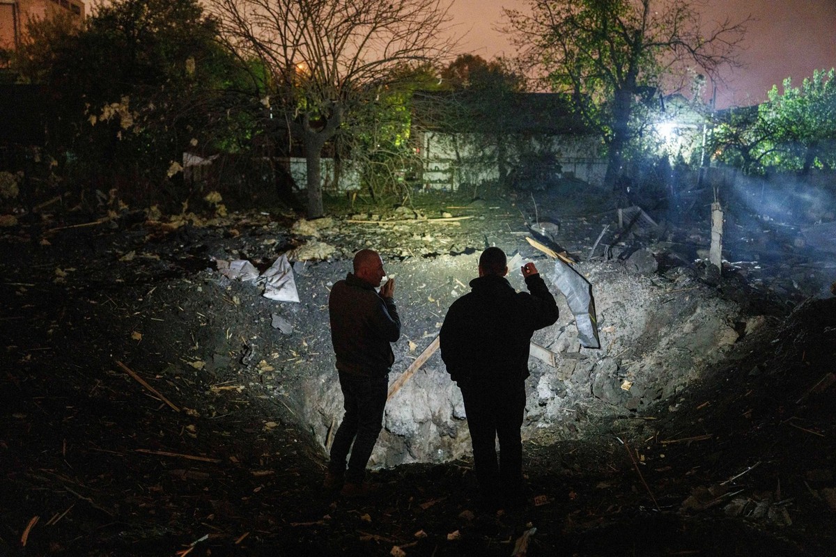 A Kiev, deux habitants observent le cratère laissé par l'impact d'un missile russe après la vague d'attaques de mercredi.