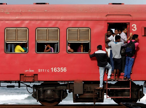 Commuters hang off a local passenger train in the morning in Colombo, Sri Lanka September 8, 2016. REUTERS/Dinuka Liyanawatte