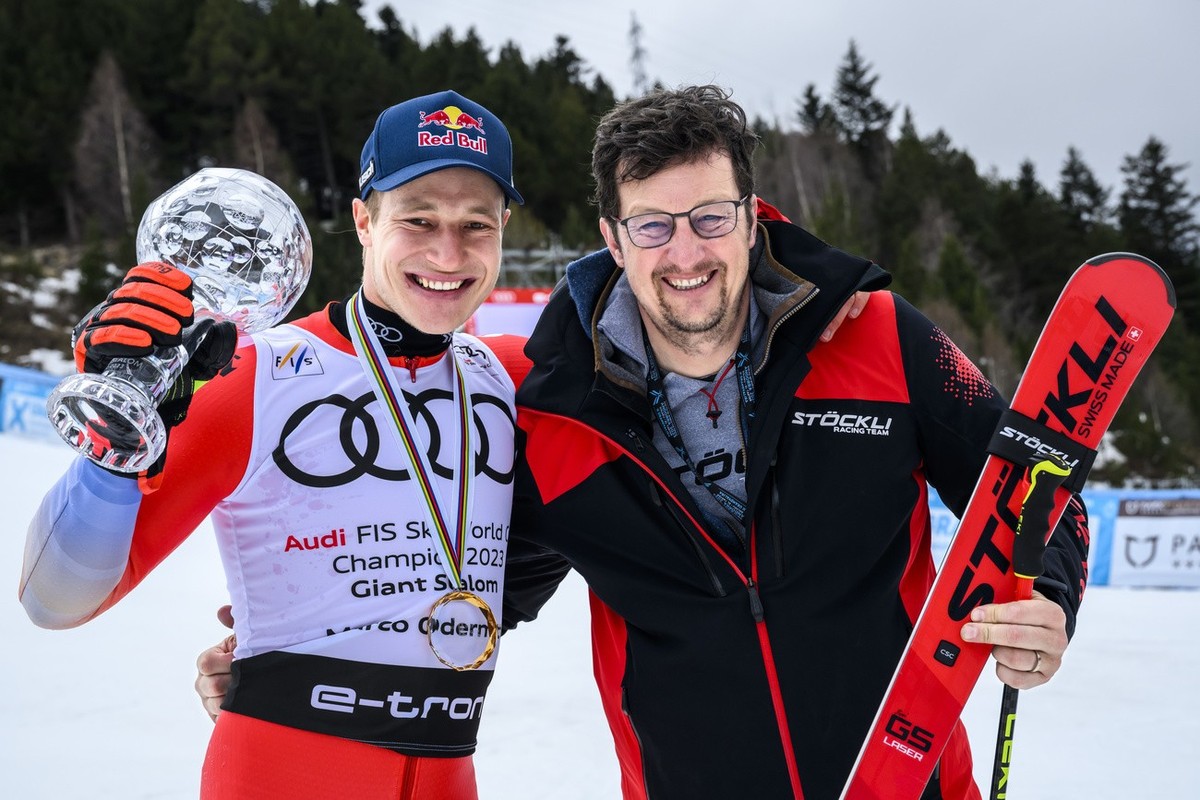Marco Odermatt of Switzerland poses with the men's giant slalom overall leader crystal globe trophy next to serviceman Chris Loedler after the podium ceremony at the FIS Alpine Skiing World Cup f ...