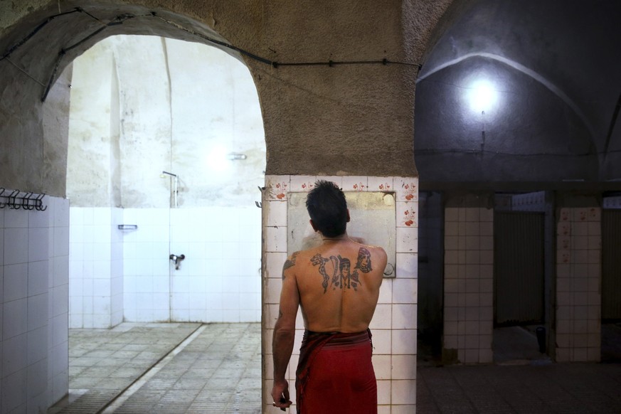 In this Jan. 9, 2015 photo, a man with Persian tattoos shaves at the Ghebleh public bathhouse, in Tehran, Iran. The steamy air and curved tiled walls of Iran’s famed public bathhouses, some rinsing an ...