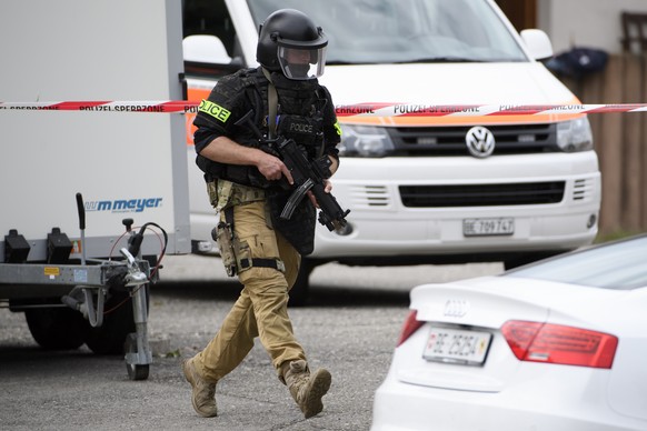 Ein Polizist am Donnerstag, 6. September 2018 in Finsterhennen. Ein Mann hat sich offenbar wegen einer drohenden Zwangsversteigerung in einem Haus verschanzt. (KEYSTONE/Anthony Anex)