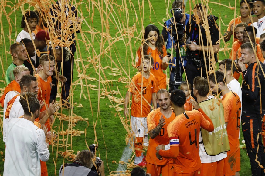 Wesley Sneijder of The Netherlands greets his teammates as he walks off the pitch with his wife Yolanthe, center top, as he retires from international soccer after the international friendly soccer ma ...