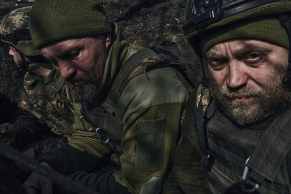 Ukrainian soldiers sit in a trench along the frontline during fighting with Russian troops near Bakhmut, Sunday, March 26, 2023. (AP Photo/Libkos)