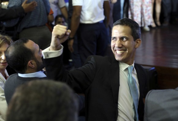 Opposition National Assembly President Juan Guaido holds up a raised fist as he waits to speak at a conference on economic plans for reviving the country at Venezuelan Central University, in Caracas,  ...