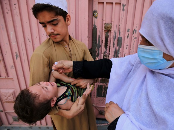 epa09252678 A health worker administers polio vaccine to children during a polio vaccination door-to-door campaign, as the spread of the coronavirus disease (COVID-19) continues, in Peshawar, Pakistan ...