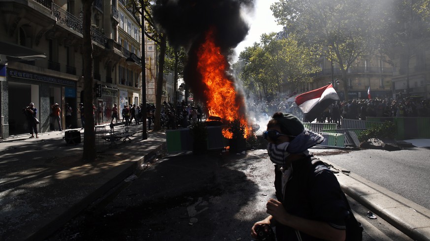 A protestor walks past a burning barricade during a climate demonstration, in Paris, Saturday, Sept. 21, 2019. Scuffles broke out in Paris between some violent activists and police which responded wit ...