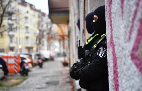 23.11.2023, Berlin: Polizeibeamte stehen bei einer Razzia in Berlin-Friedrichshain am Eingang eines Geb