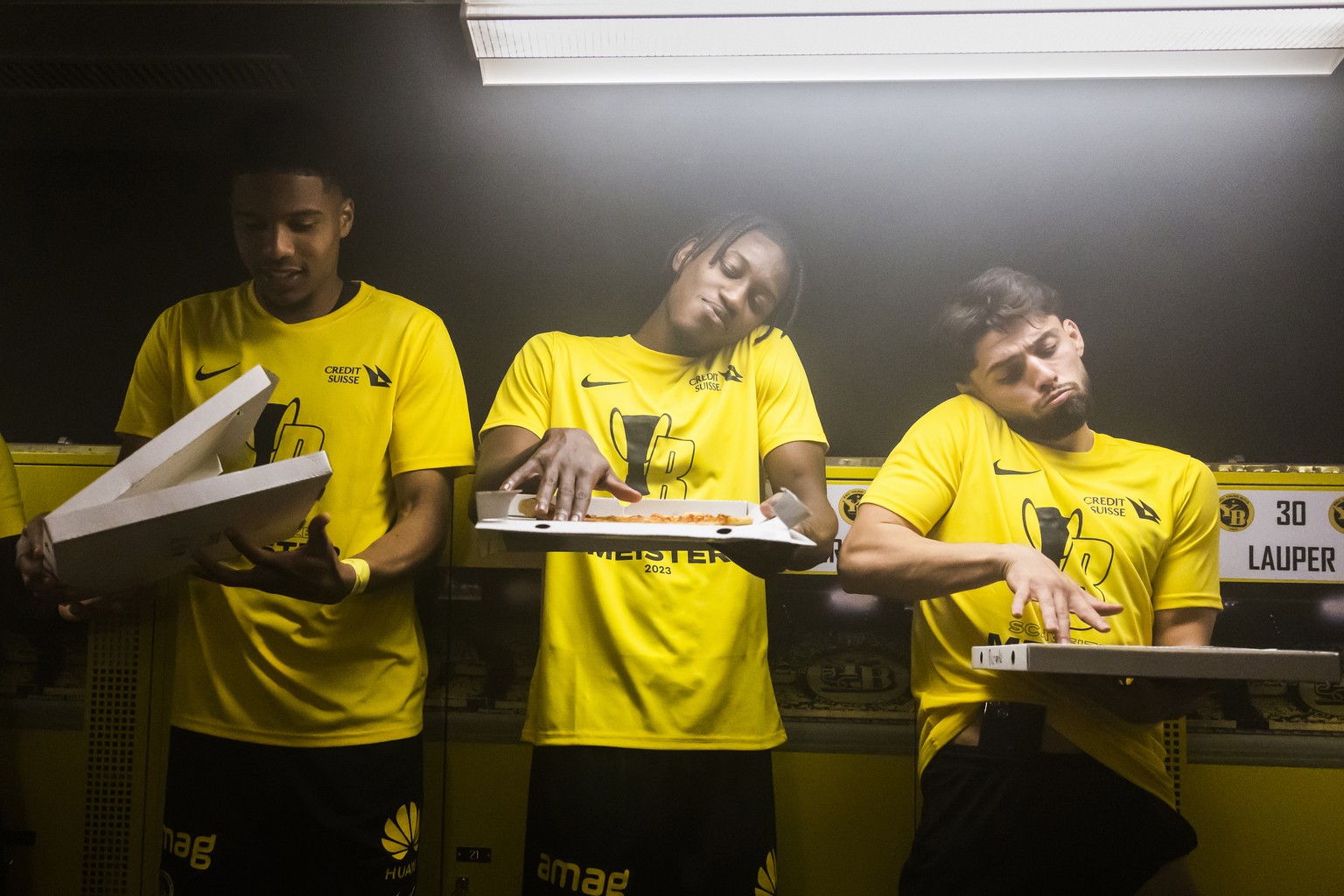 YBs Aurele Amenda, Joel Monteiro und Kastriot Imeri, von links, imitieren einen DJ auf einer Pizzaschachtel, bei der Meisterfeier mit Pizza, Bier und Prosecco in der Umkleidekabine des Teams, nach dem ...