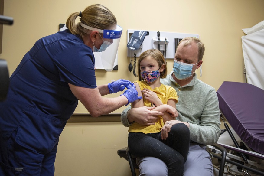 Sutton Gilliam, 7, a first grader at Potter Gray Elementary, sits on her father Timothy&#039;s lap as she receives her Pfizer COVID-19 vaccine from Med Center Urgentcare Ultrasonographer Irene Garrett ...