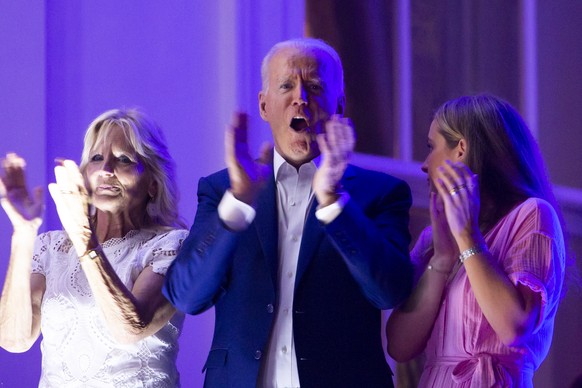 epa09322912 US President Joe Biden (C) and First Lady Jill Biden (L), with granddaughter Finnegan Biden (R) applaud after watching fireworks on the National Mall from the Truman balcony of the White H ...