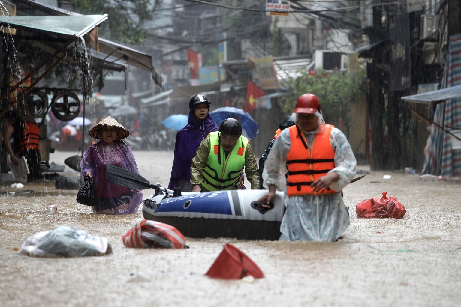 epa11598423 People push an inflatable boat through the flood waters in a street of Hanoi, Vietnam, 11 September 2024. Typhoon Yagi, which struck northern Vietnam over the weekend, triggered severe flo ...