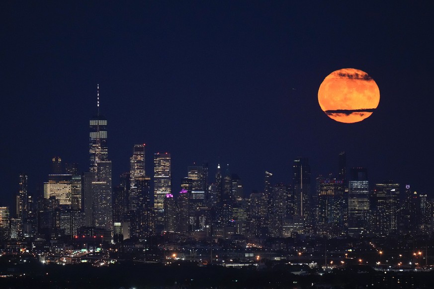 The moon rises through clouds over the skyline of lower Manhattan in this view from West Orange, N.J., Tuesday, Aug. 1, 2023. The first of two supermoons in August graced the skies on Tuesday. A super ...