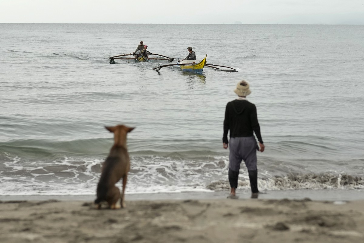 A fisherman and a dog watch as boats arrive during beach seine fishing in Tanauan, Leyte, Philippines on Wednesday, Oct. 26, 2022. Years of market pressures, lack of fisheries management and unchecked ...