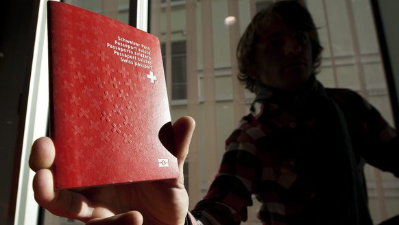 Un homme tient un passeport biometrique Suisse dans le nouveau centre de biometrie au Flon ce vendredi 21 janvier 2011 a Lausanne. Ce centre va recolter les donnees biometriques pour les passeports su ...