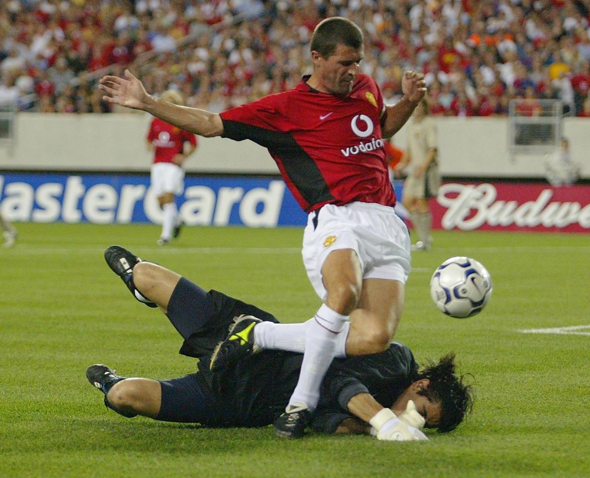 Roy Keane (top) midfielder and captain of Manchester United runs over F.C. Barcelona's goal keeper Victor Valdes (on the ground) as Keane tries for a goal in the first half of the Champions World ...